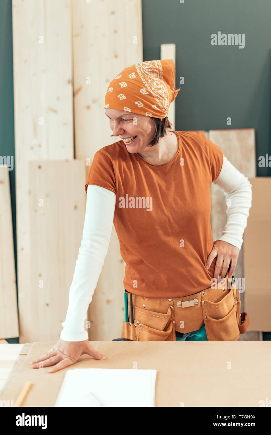 Self employed female carpenter smiling portrait in her small business woodwork workshop Stock Photo
