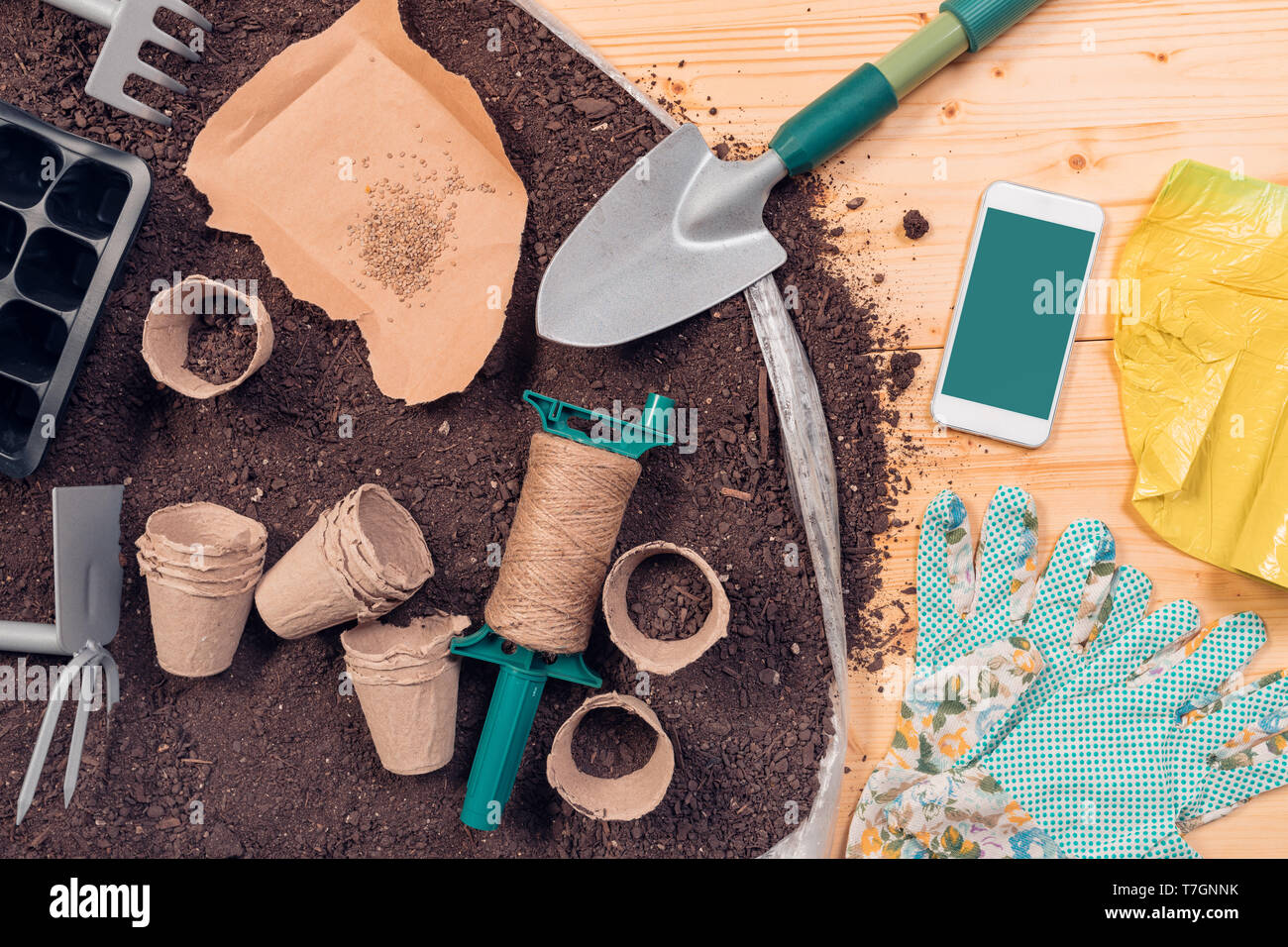 Smartphone screen mock up for gardening and seeding app with tools and equipment on potting soil Stock Photo