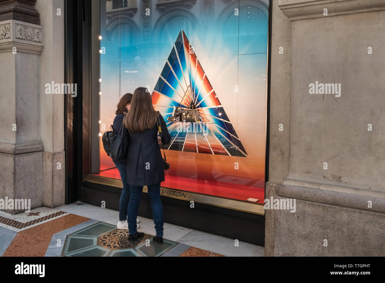Galleria Vittorio Emanuele II shopping arcade, Milan, Italy, two women looking at luxury high end fashion brand Louis Vuitton designs in shop window. Stock Photo