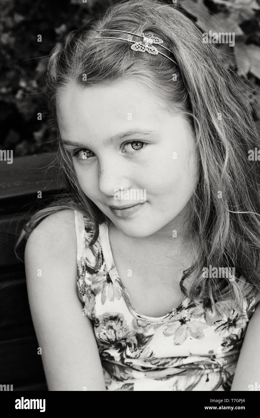 Beautiful young girl is sitting on the bench at park in summer Stock ...