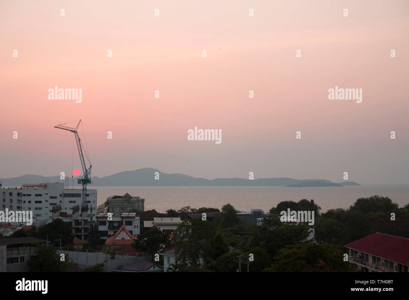 Building on the sea cost. Construction equipment at pink sunset. Real estate on the beach. Stock Photo