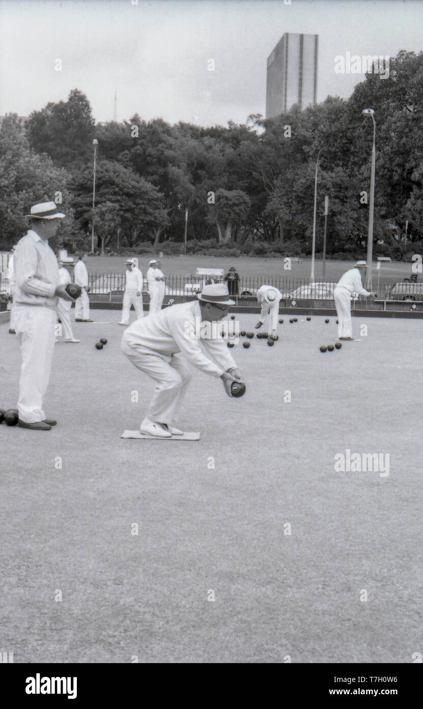 1977 Sydney, Australia: Middle aged and older Australian men playing lawn bowls at the former bowling green on College Street. The bowls club was established in 1880 and removed in 1997 as part of a major renovation of the area in front of St Mary's Cathedral. The background in the image shows the trees bordering Hyde Park and a notable lack of sky scrapers that exist today. The only building visible is the Hilton Hotel that was subjected to a bomb explosion killing three people a year later in 1978 Stock Photo