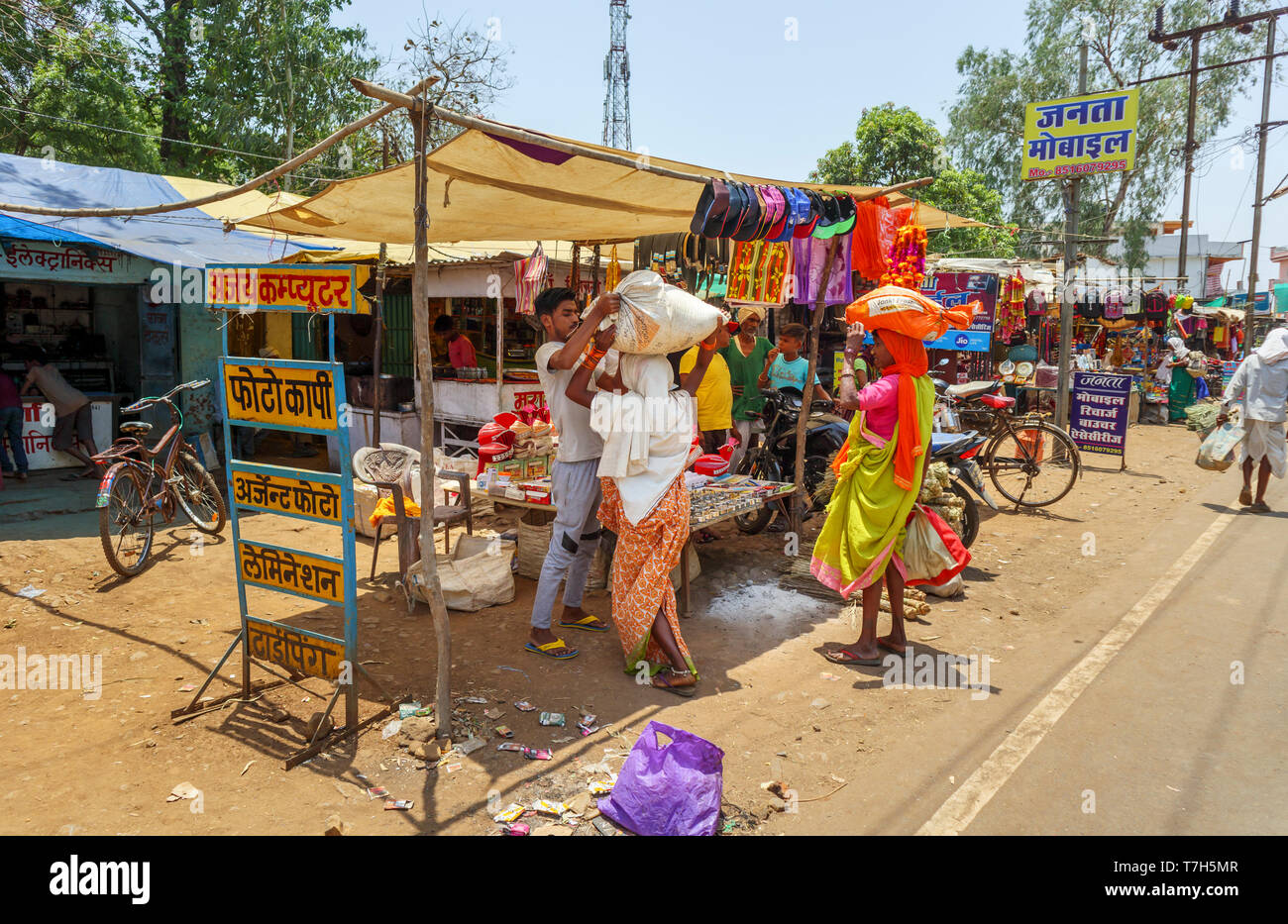 Street scene in Shahpura, a Dindori district town in the central Indian state of Madhya Pradesh, local women carry  packages on their heads Stock Photo