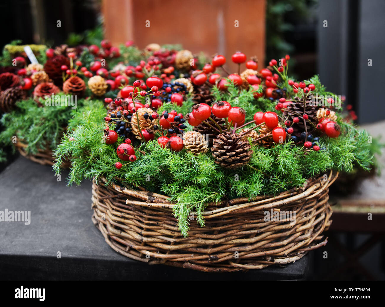 Traditional european Christmas decoration with fir-tree, pinecones and berries of dogrose in a twiggen basket. Stock Photo