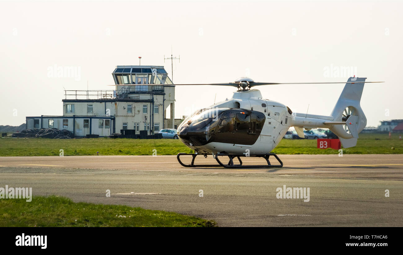 Helicopter about to lift off with control tower in nthe background Stock Photo
