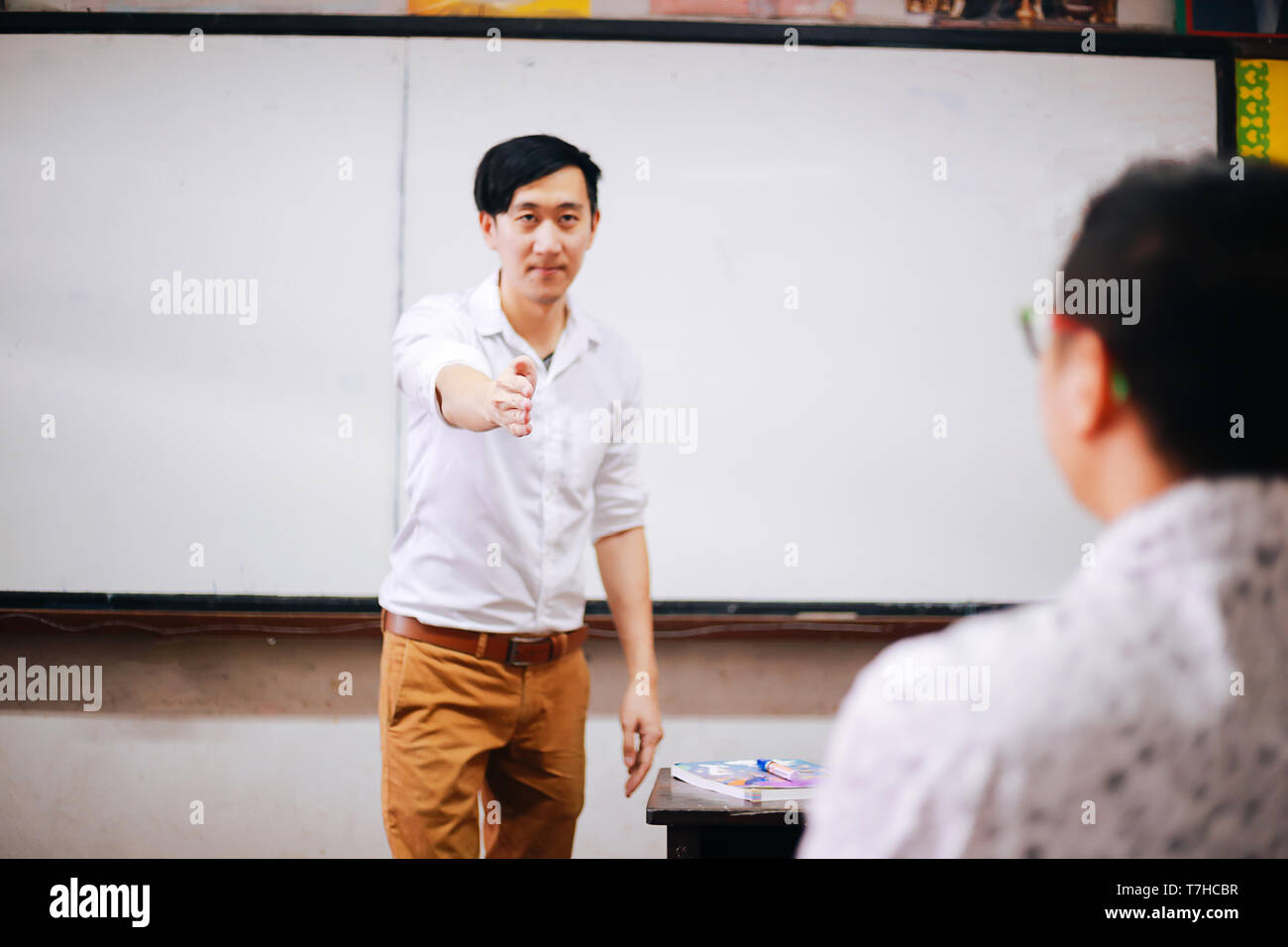 Asian man talking to student while having class in spacious auditorium Stock Photo