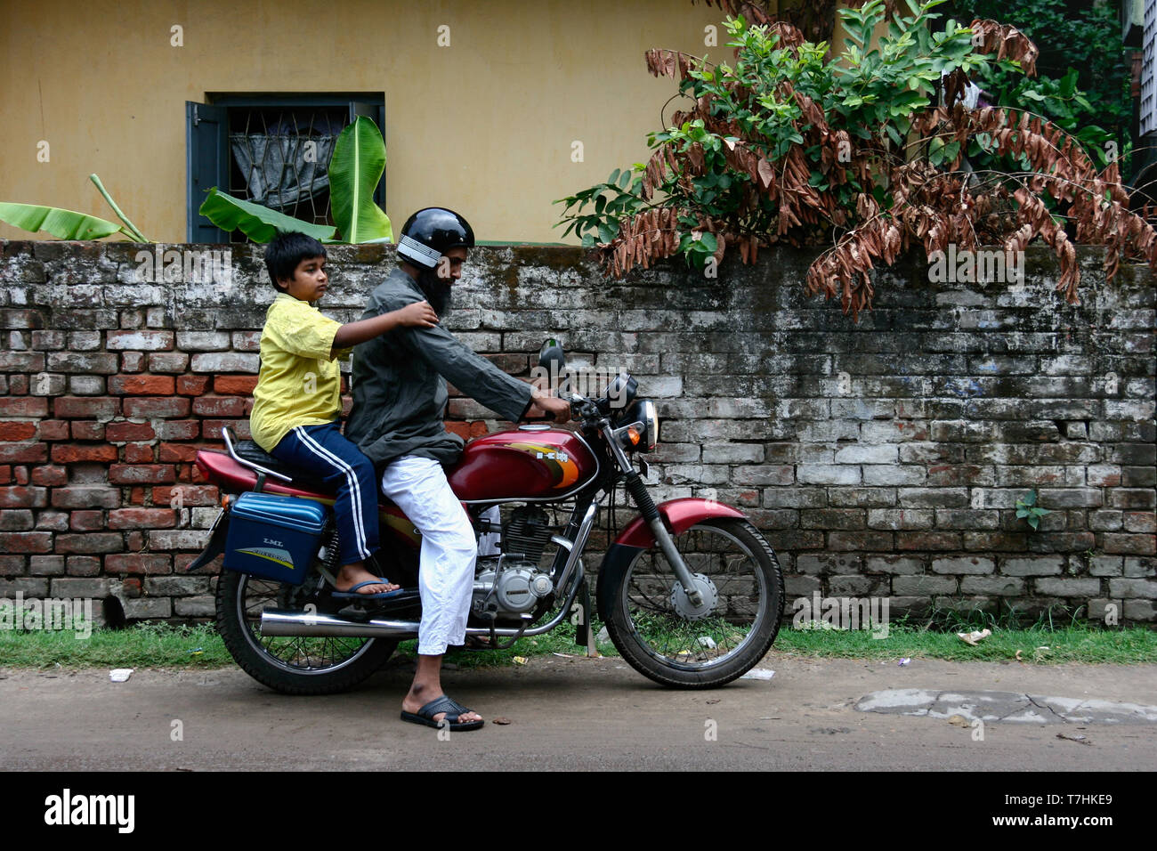 Kolkata, India - February 4, 2019 : local indian father try to starting old motorcycle to sending his child to school in the morning. indian child boy Stock Photo
