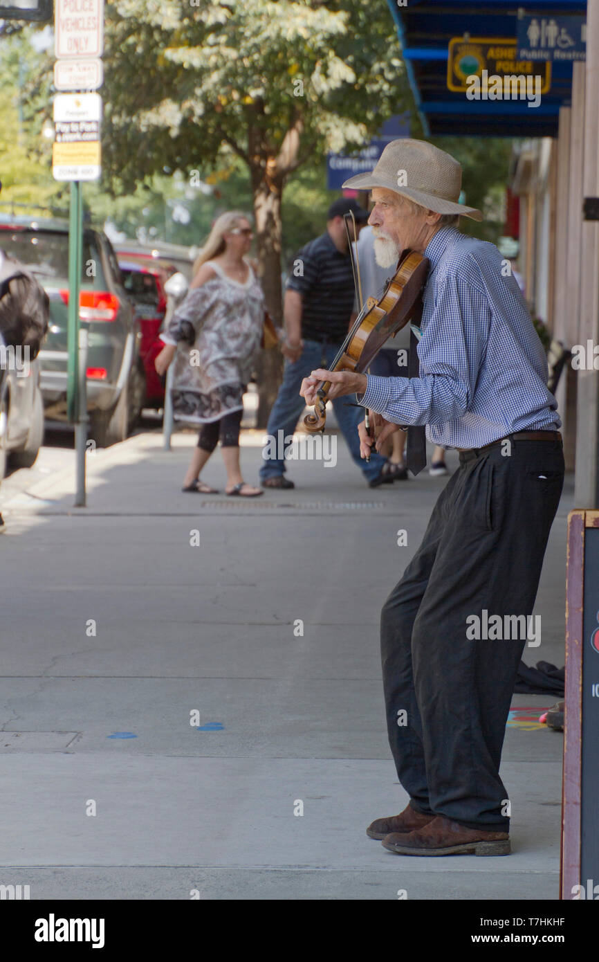 ASHEVILLE, NORTH CAROLINA, USA - September 9, 2018: An older violin player plays solo for tips on a busy downtown Asheville street on September 9, 201 Stock Photo