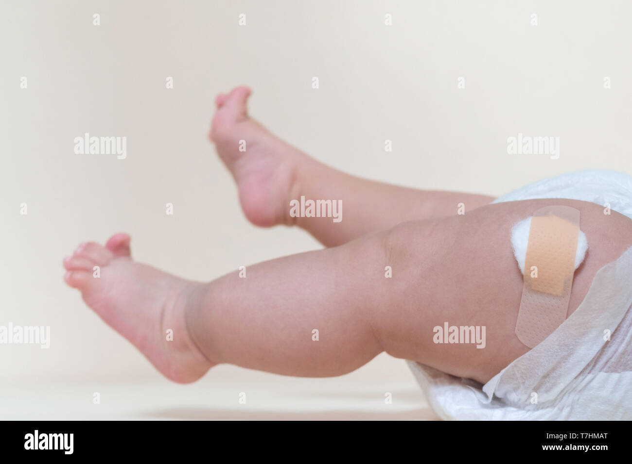 baby boy legs with a band-aid patch after taking a vaccine. doctor or nurse putting plaster on baby leg at the hospital. Stock Photo