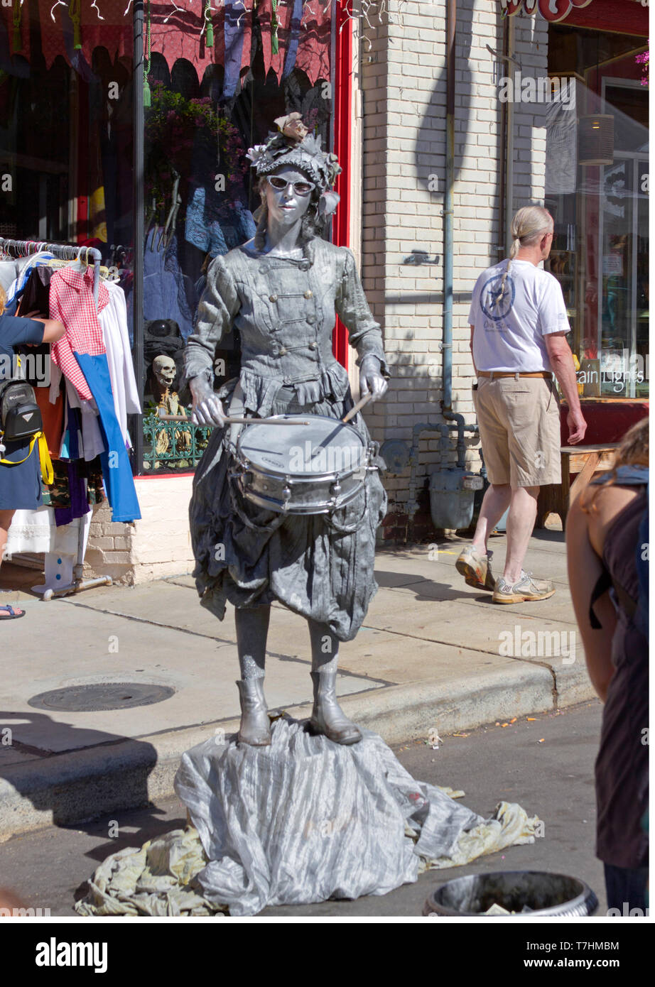 ASHEVILLE, NORTH CAROLINA, USA – 9/5/2010: A popular human statue known as the Silver Drummer Girl busks in downtown Asheville, holding still then com Stock Photo