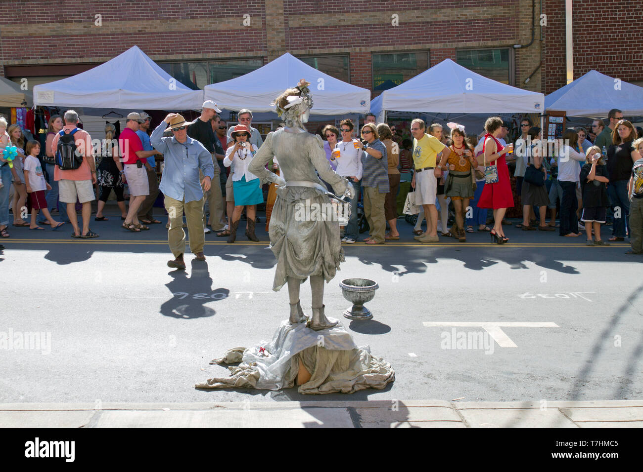 ASHEVILLE, NORTH CAROLINA, USA – 9/5/2010: A popular human statue busker known as the Silver Drummer Girl entertains crowds in the street as she holds Stock Photo