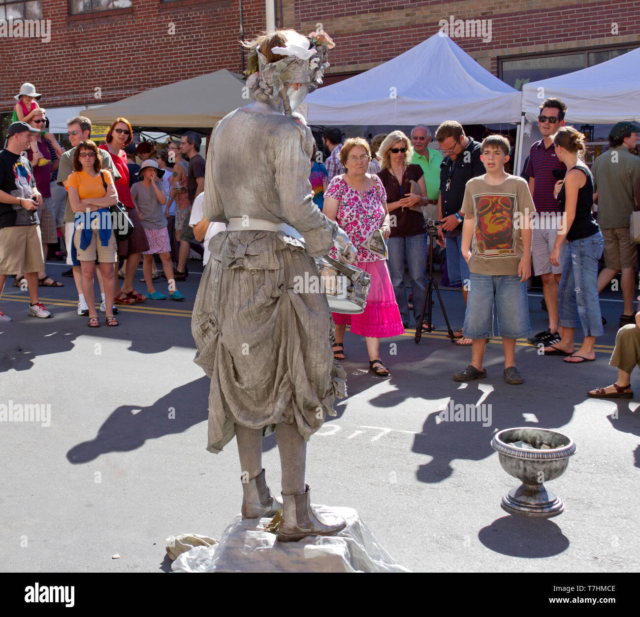 ASHEVILLE, NORTH CAROLINA, USA – 9/5/2010: An amazing and popular human statue, a busker known as the Silver Drummer Girl, entertains crowds in the st Stock Photo