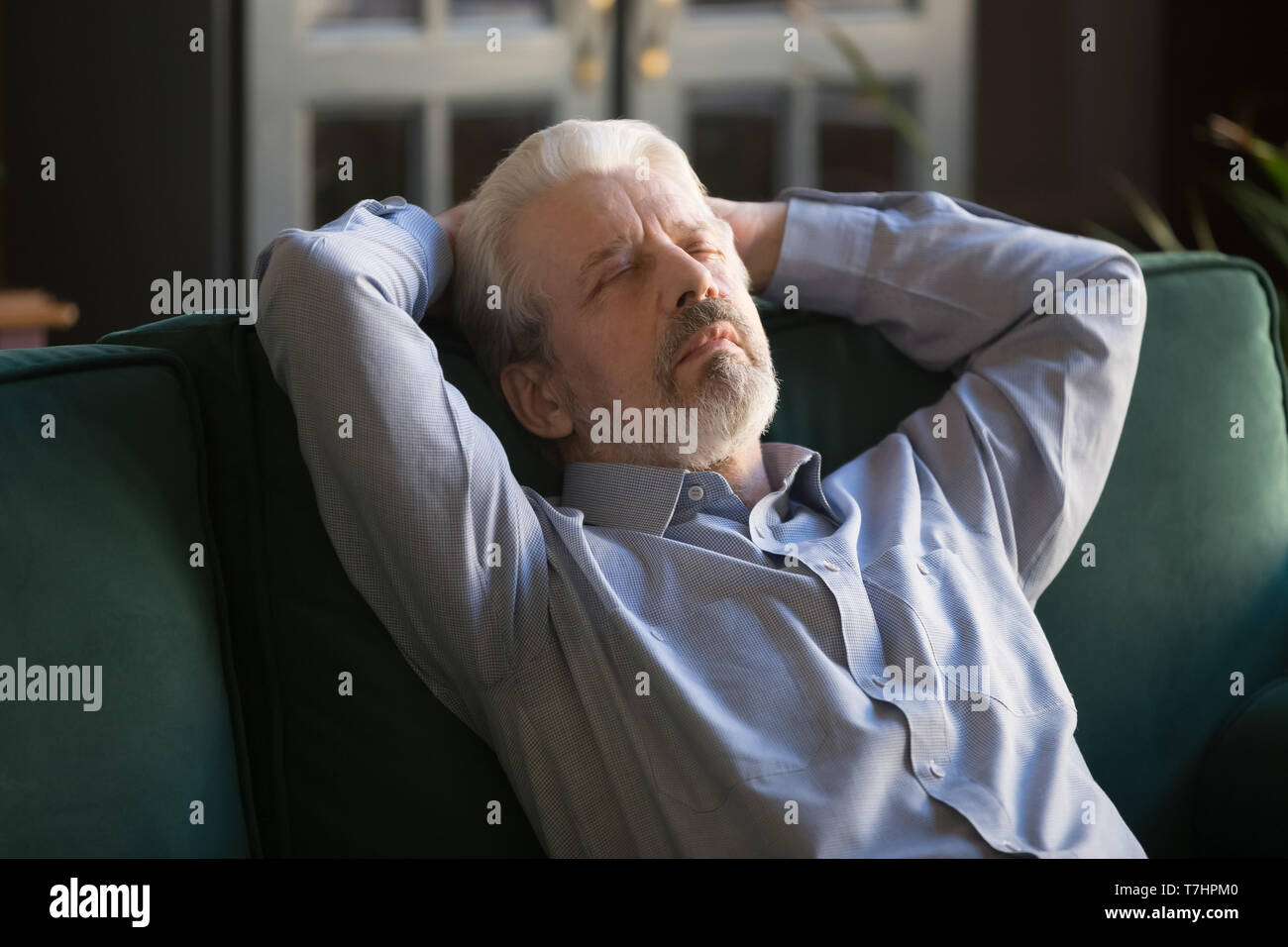 Sleeping grey haired man relaxing on comfortable sofa at home Stock Photo