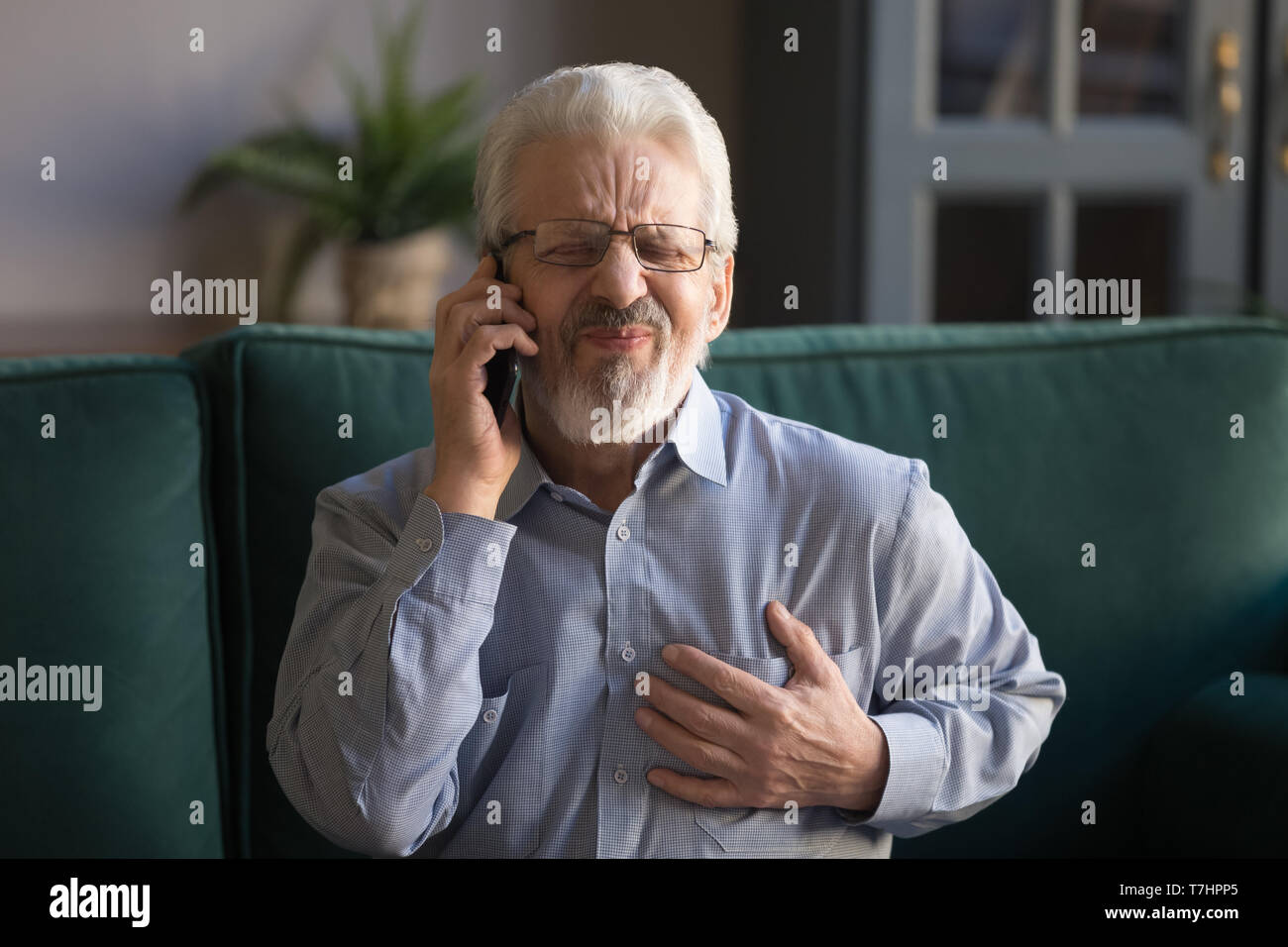 Grey haired man touching chest, having heart attack, calling emergency Stock Photo
