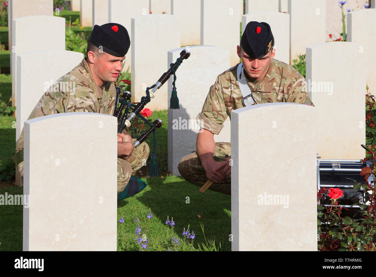 A piper and a drummer of the Black Watch honoring the fallen at the World War II Ranville War Cemetery in Normandy, France Stock Photo