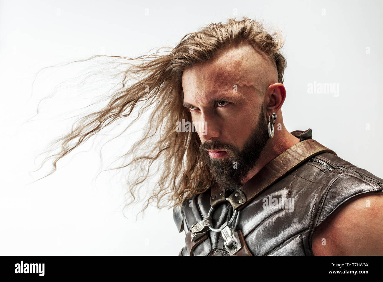 Seriously looking. Blonde long hair and muscular male model in leather  viking's costume with the big hammer cosplaying Thor isolated on white  studio background. Fantasy warrior, antique battle concept Stock Photo -
