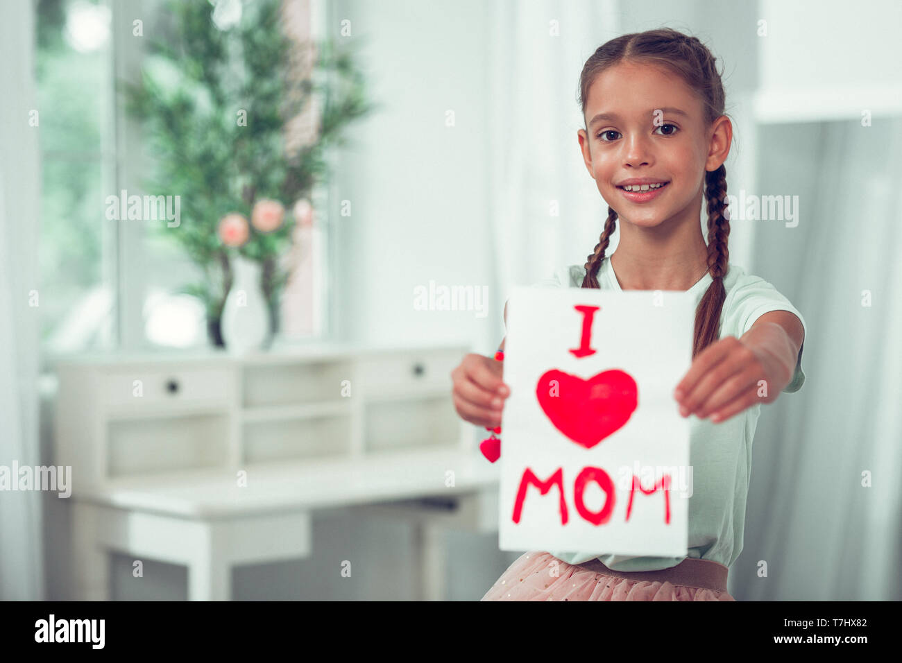 Nice-looking Afro-American girl showing picture with I love mom sign. Stock Photo