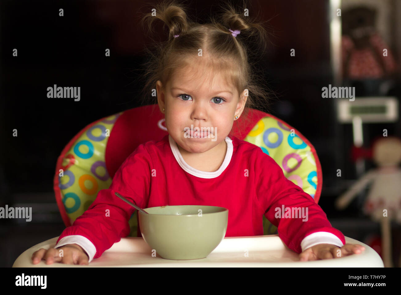 portrait of little girl looking at camera and licking her lips after eating porridge Stock Photo