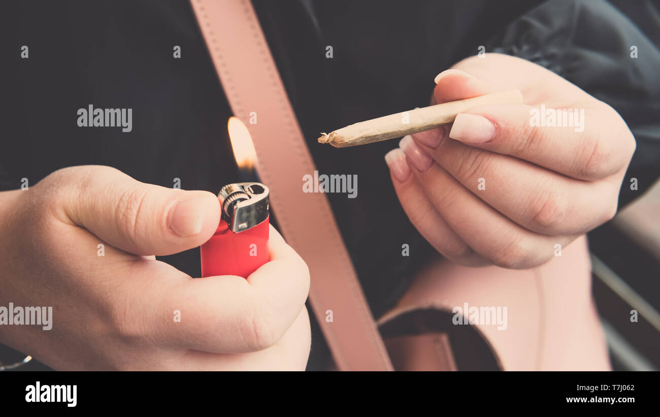 Marijuana joint in the female hand close-up. Woman smoking medical marijuana joint uotdoors. Cannabis Stock Photo