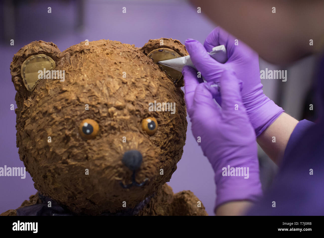 A chocolatier adds the finishing touches on a giant chocolate teddy bear made for the announcement of a new royal baby at Cadbury World in Birmingham. Stock Photo