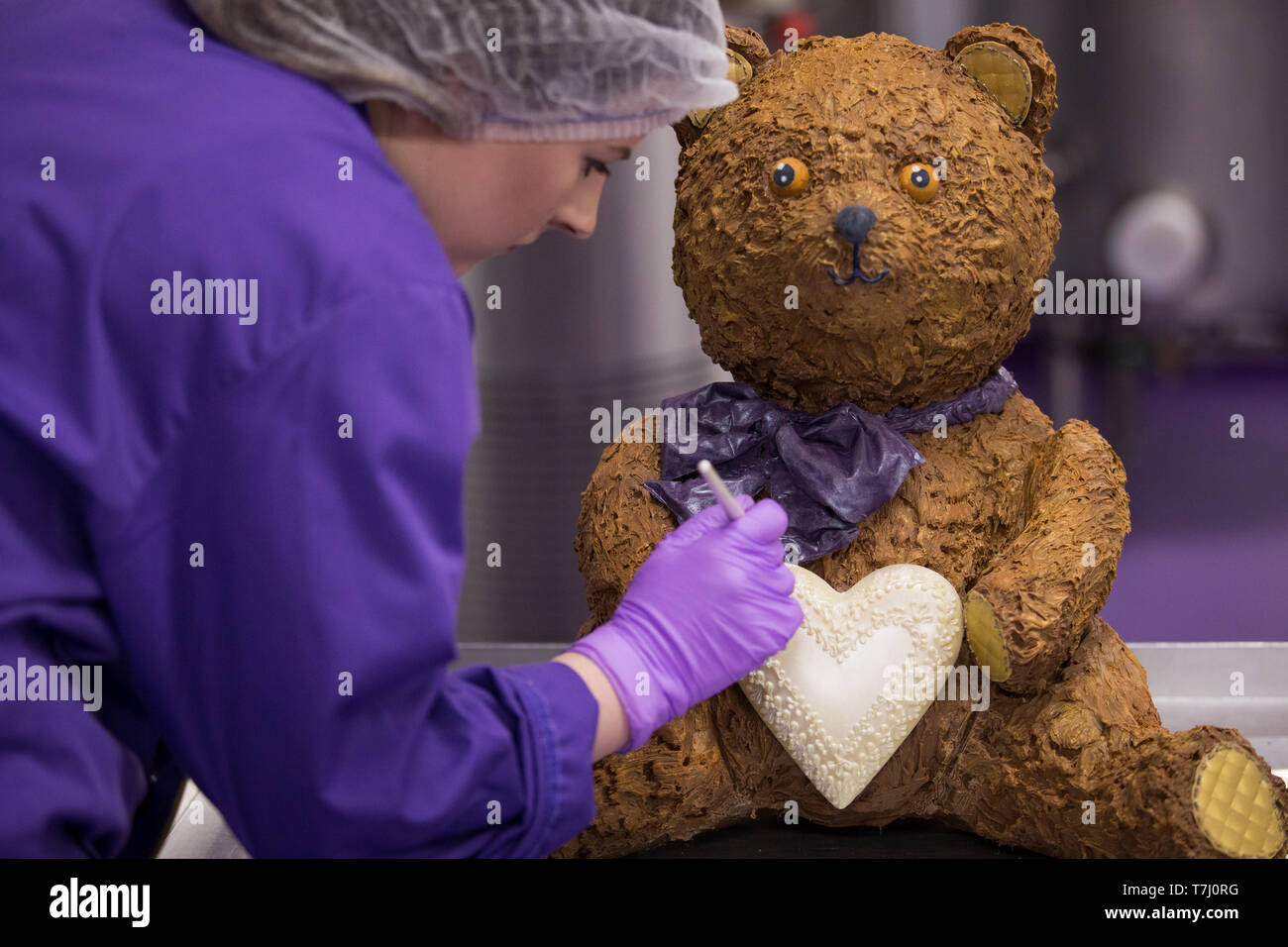 A chocolatier adds the finishing touches on a giant chocolate teddy bear made for the announcement of a new royal baby at Cadbury World in Birmingham. Stock Photo