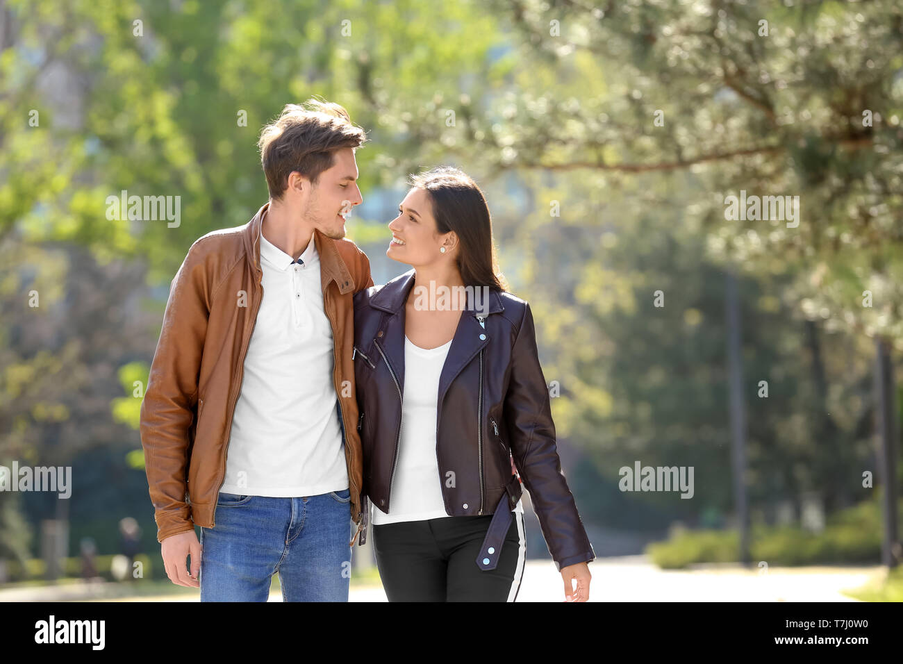 Happy young couple walking together in city park Stock Photo - Alamy