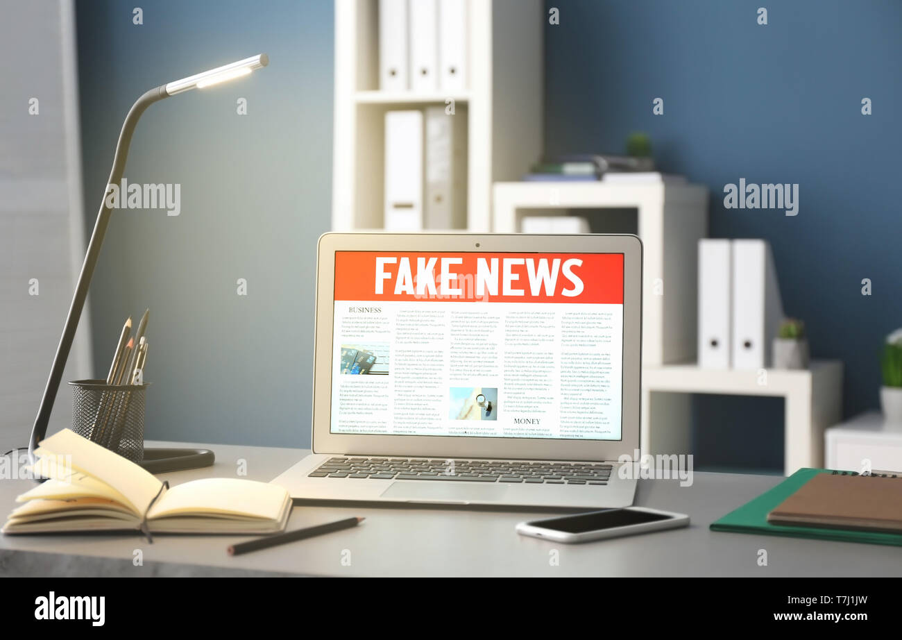 Workplace with laptop and fake news on screen Stock Photo - Alamy