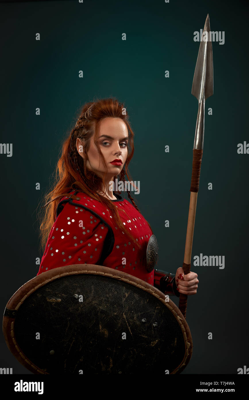 Brave female warrior wearing in red medieval costume looking at camera