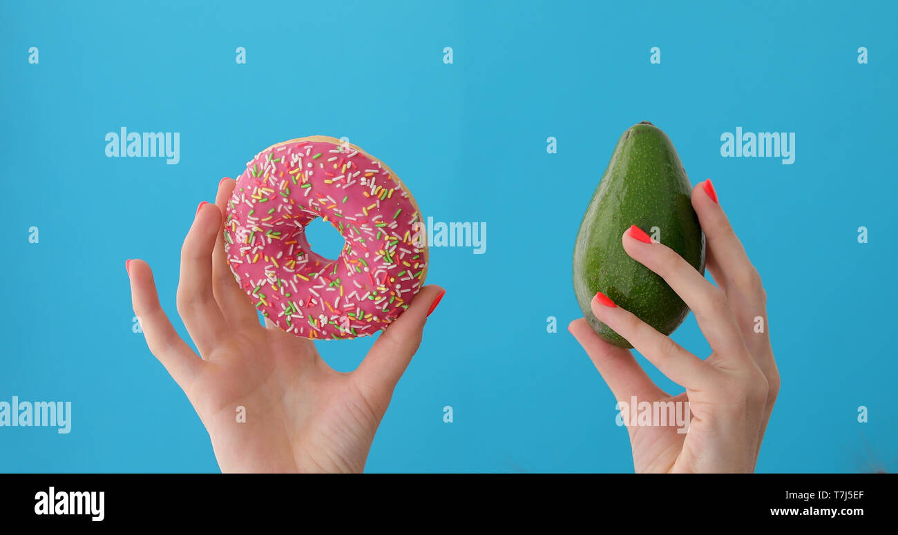 Hands holding avocado and donut Stock Photo