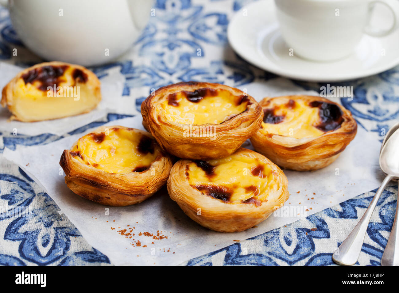 Egg tart, traditional Portuguese dessert, pastel de nata on a parchment paper. Blue background. Stock Photo