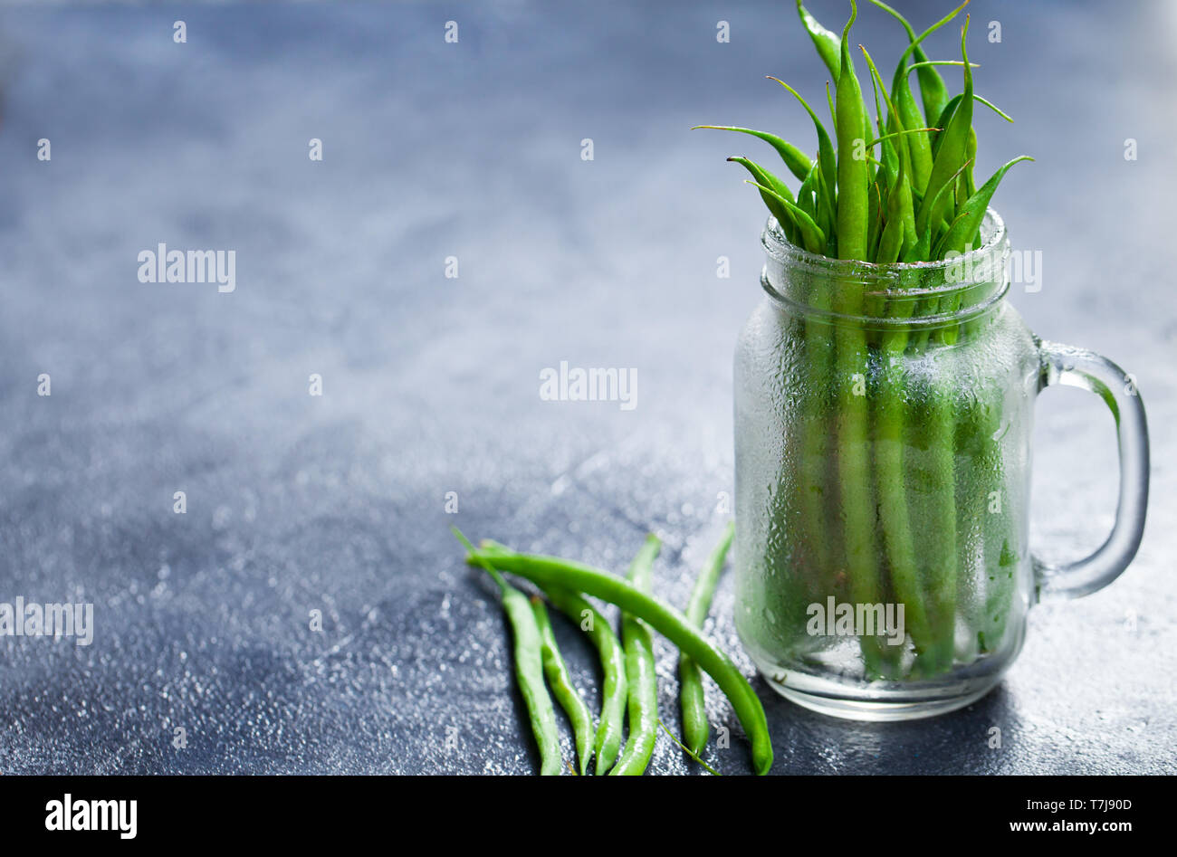 Green beans in glass jar on grey stone background. Copy space. Stock Photo