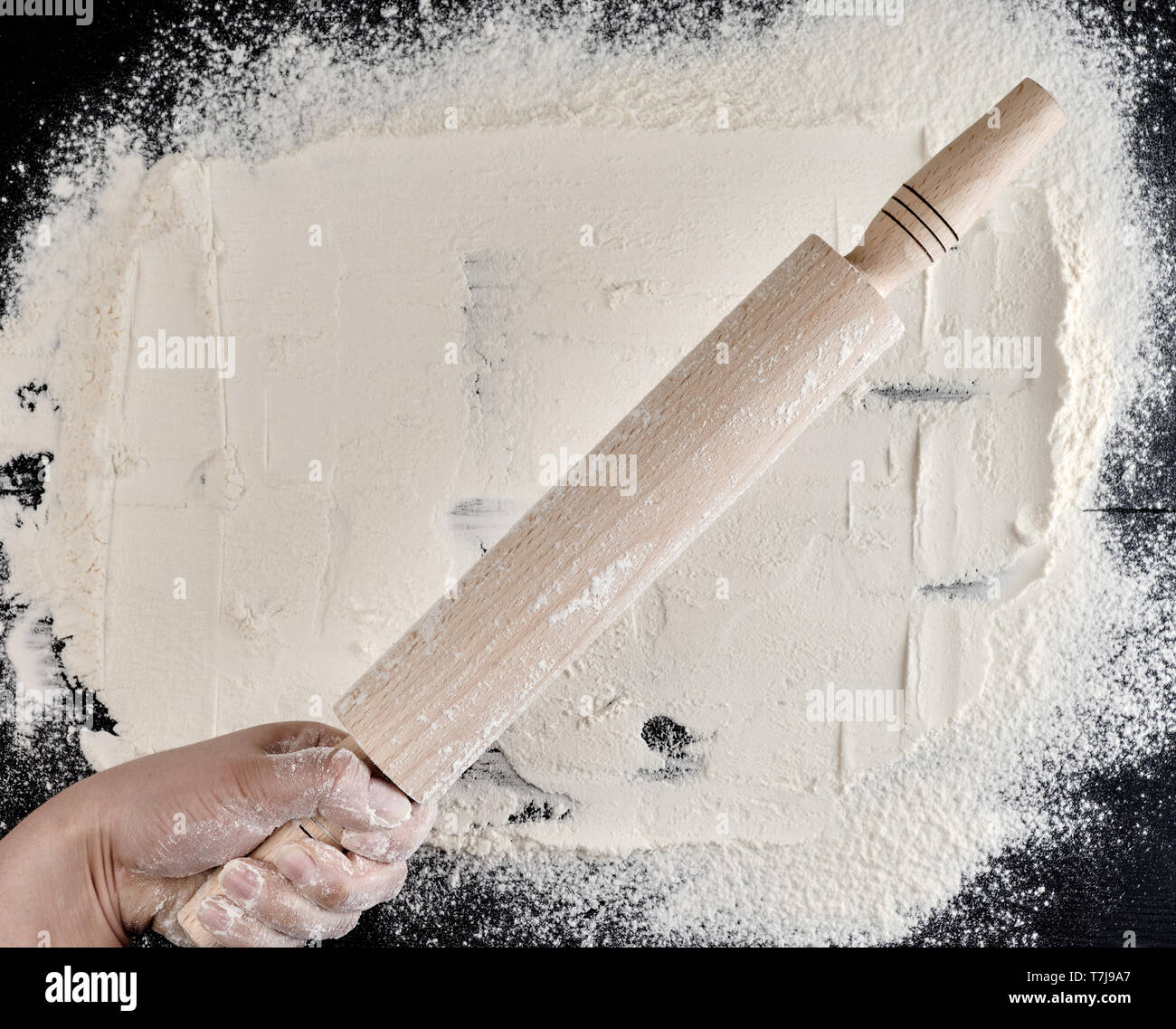 Pin Over woman's hand holding a wooden rolling pin over the table with flour ...