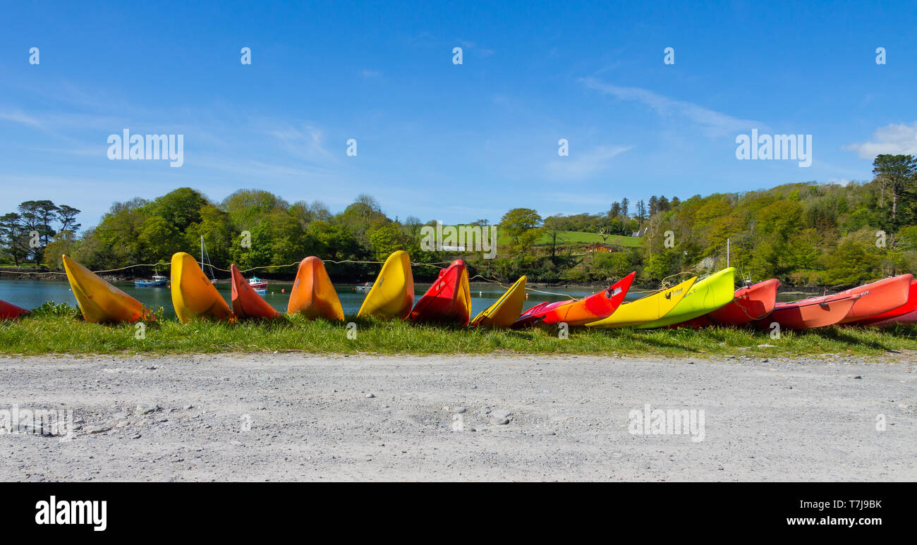 rows of brightly coloured kayaks on the side of a track by the seashore Stock Photo