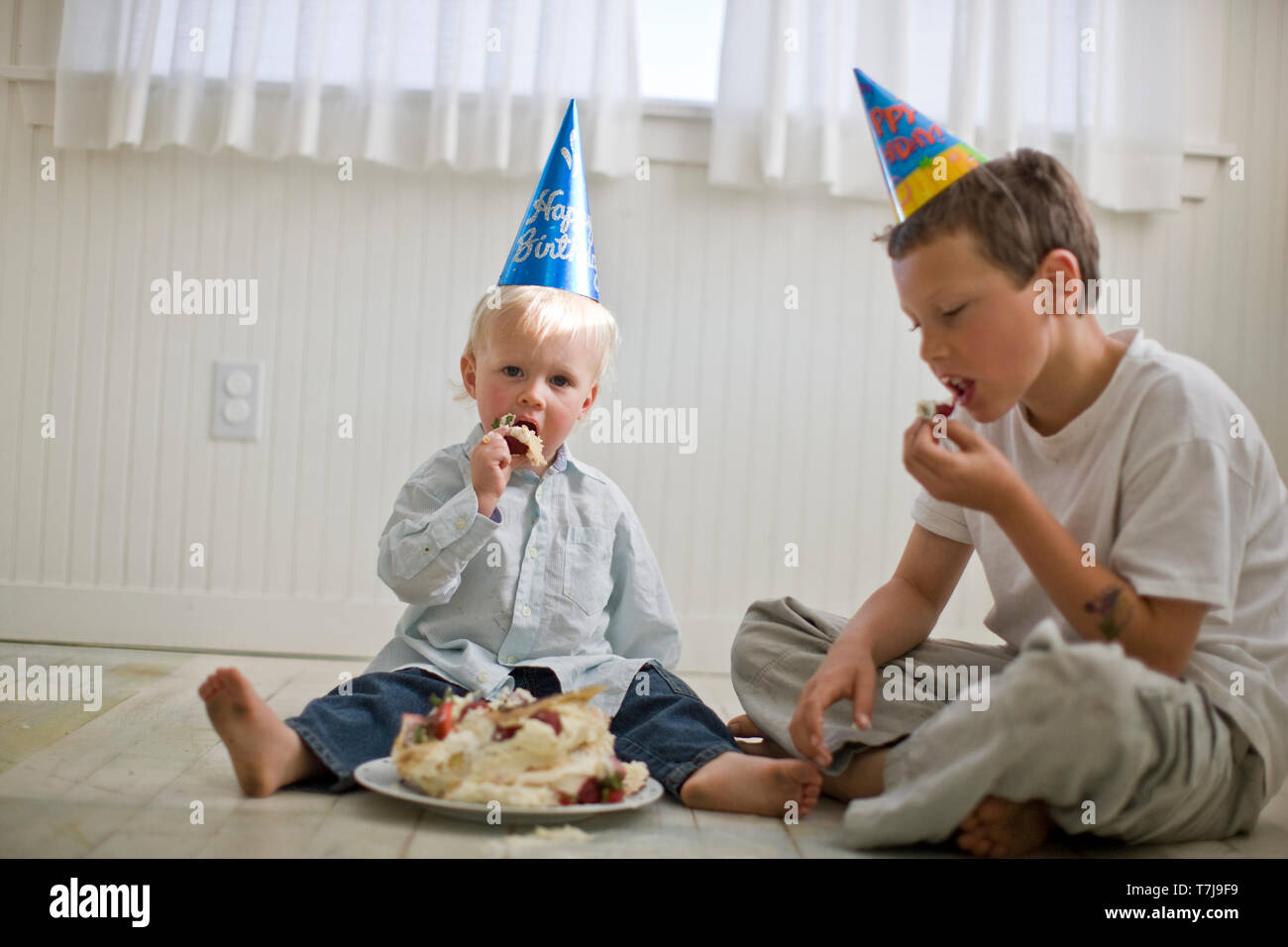 Two young boys eating a cake that has been squashed Stock Photo