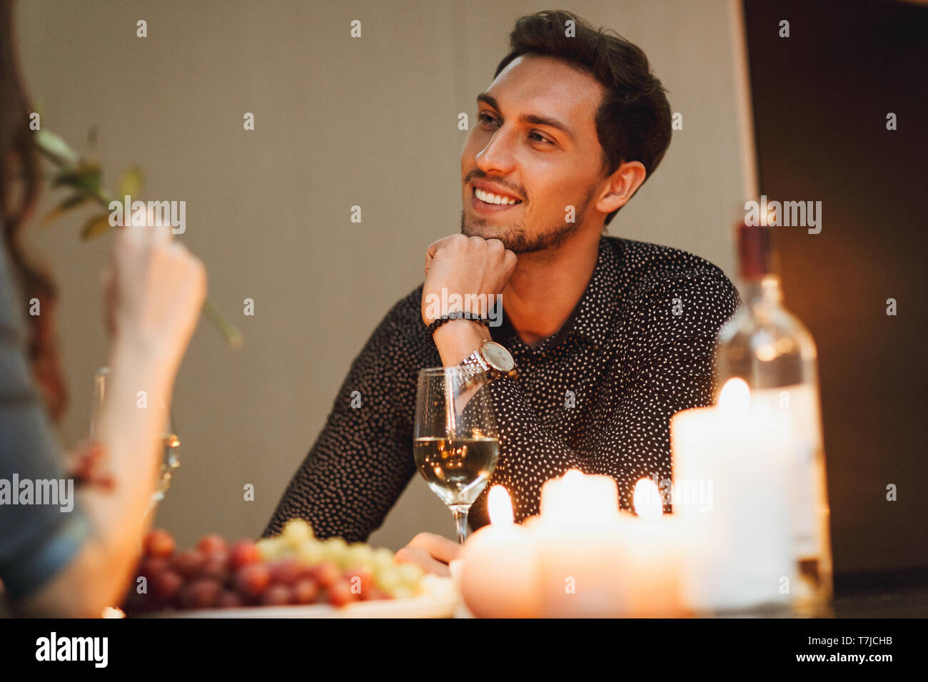 Beautiful passionate couple having a romantic candlelight dinner at home, drinking wine
