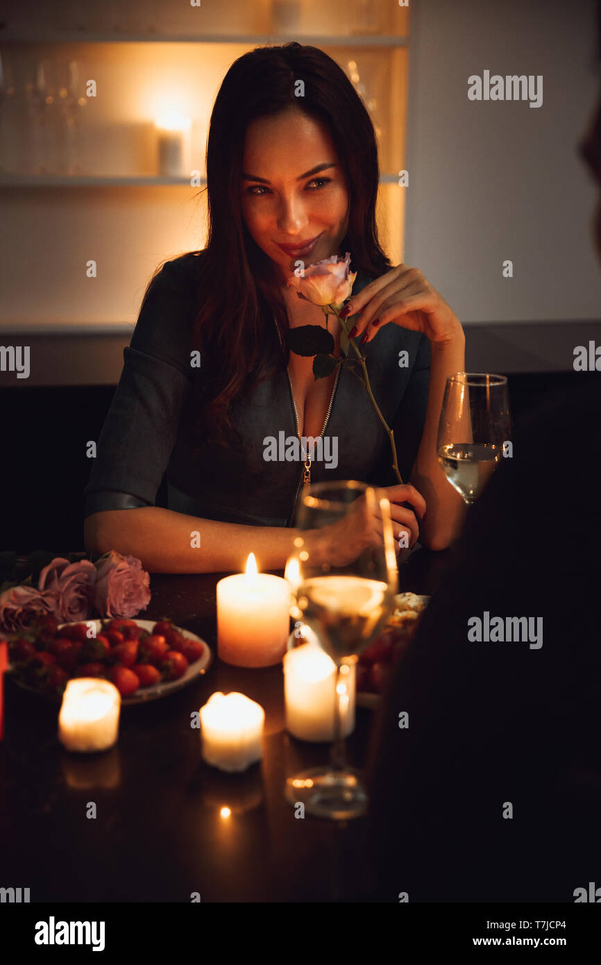 Beautiful passionate couple having a romantic candlelight dinner at home, woman smelling a