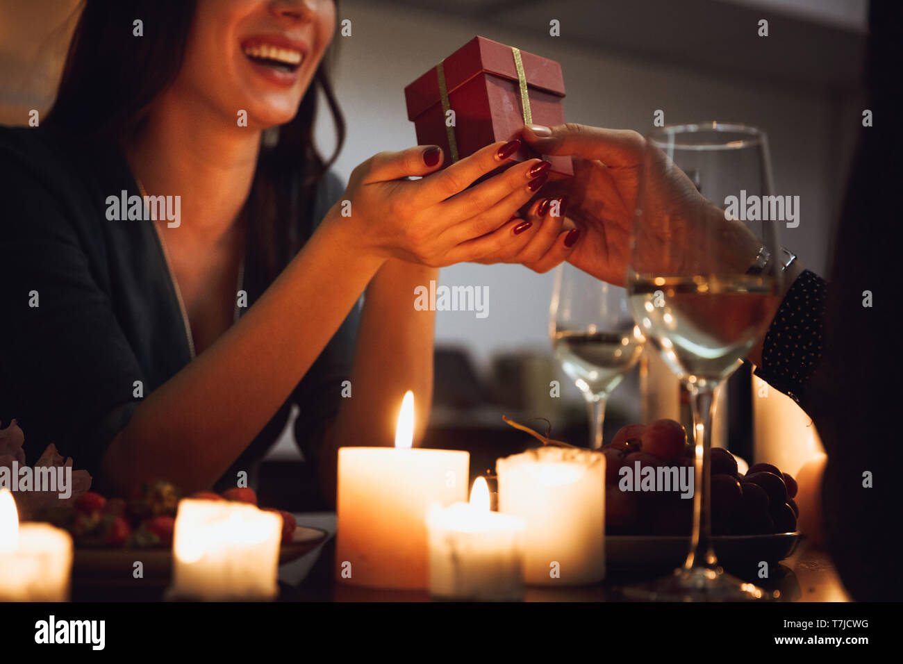 Beautiful passionate couple having a romantic candlelight dinner at home, drinking wine, woman