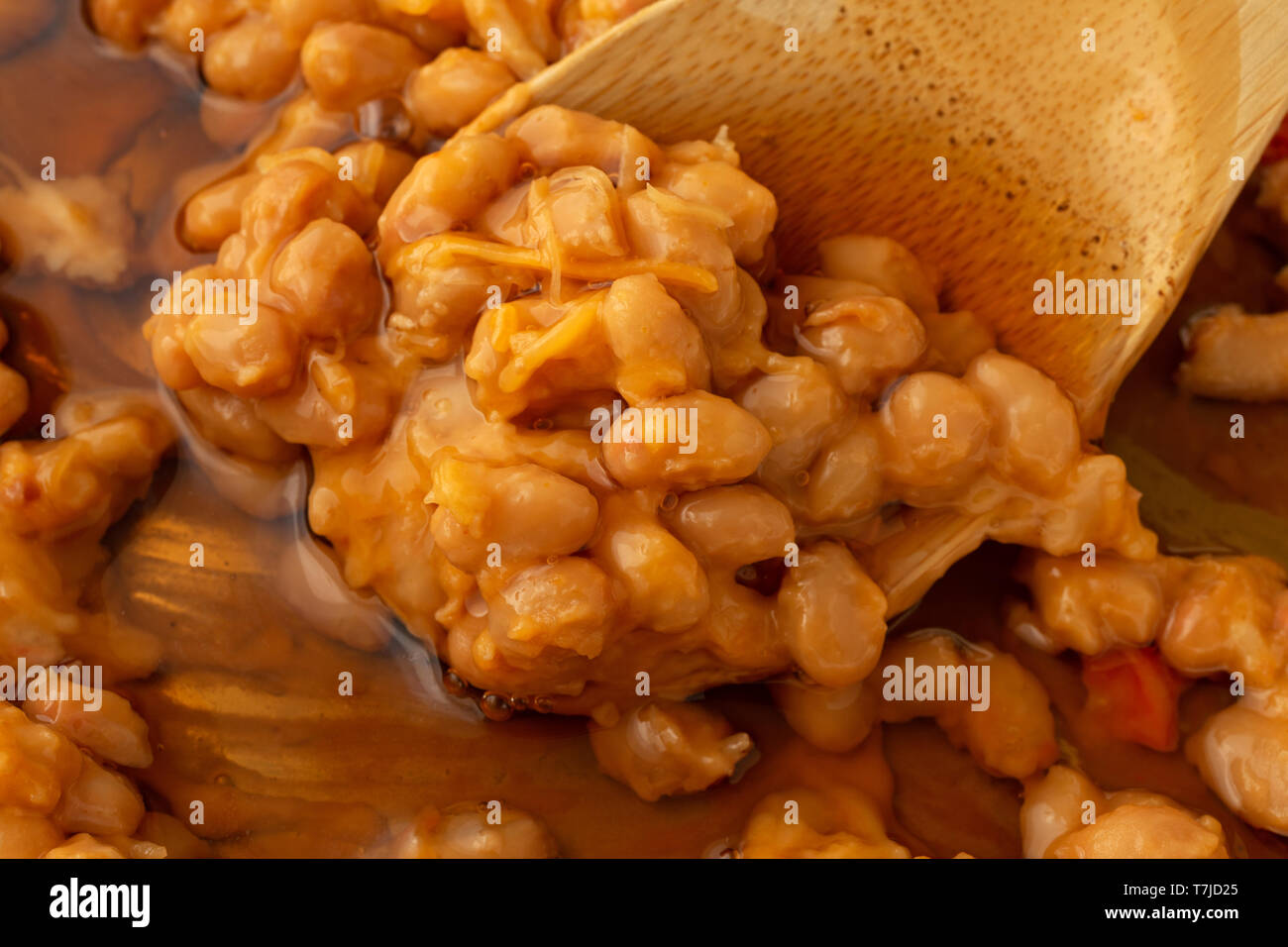 Close view of baked beans with cheese and bacon in a tomato sauce plus