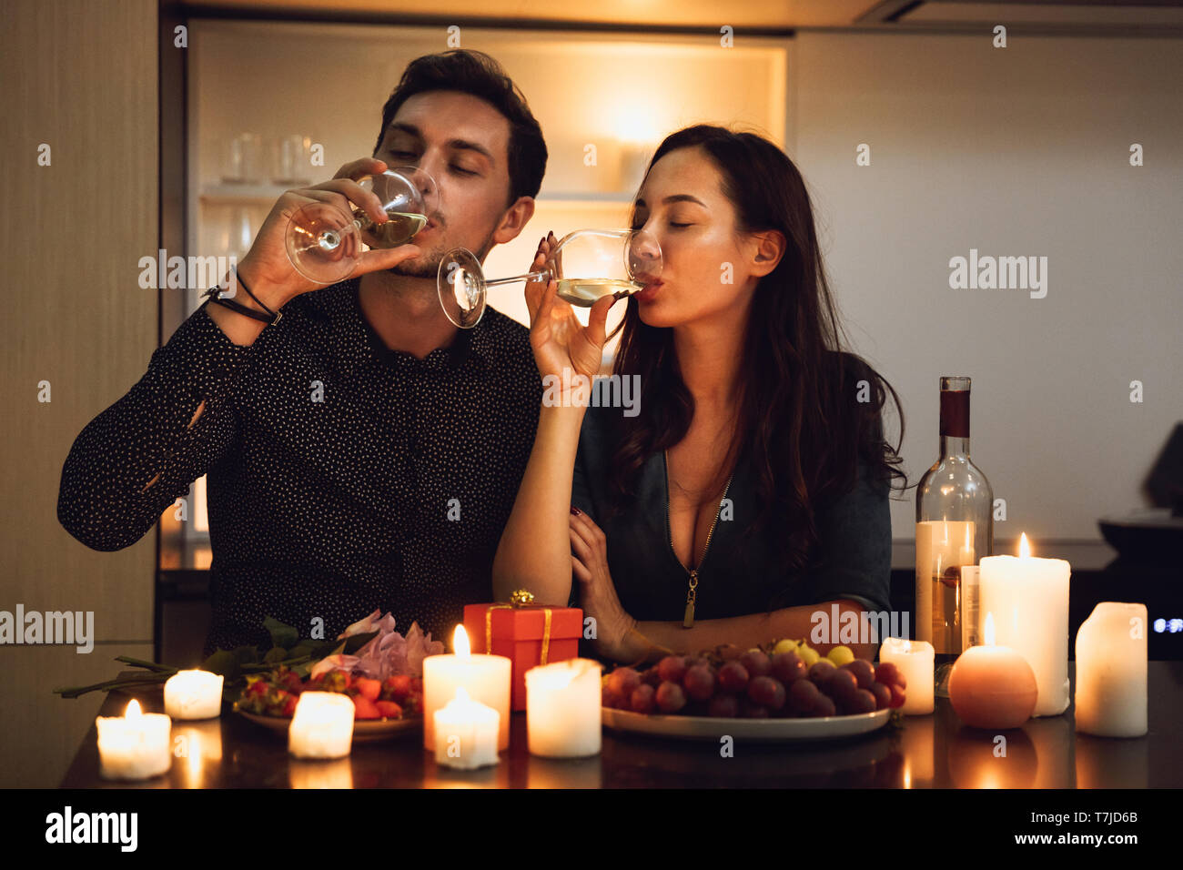 Beautiful passionate couple having a romantic candlelight dinner at home, drinking wine