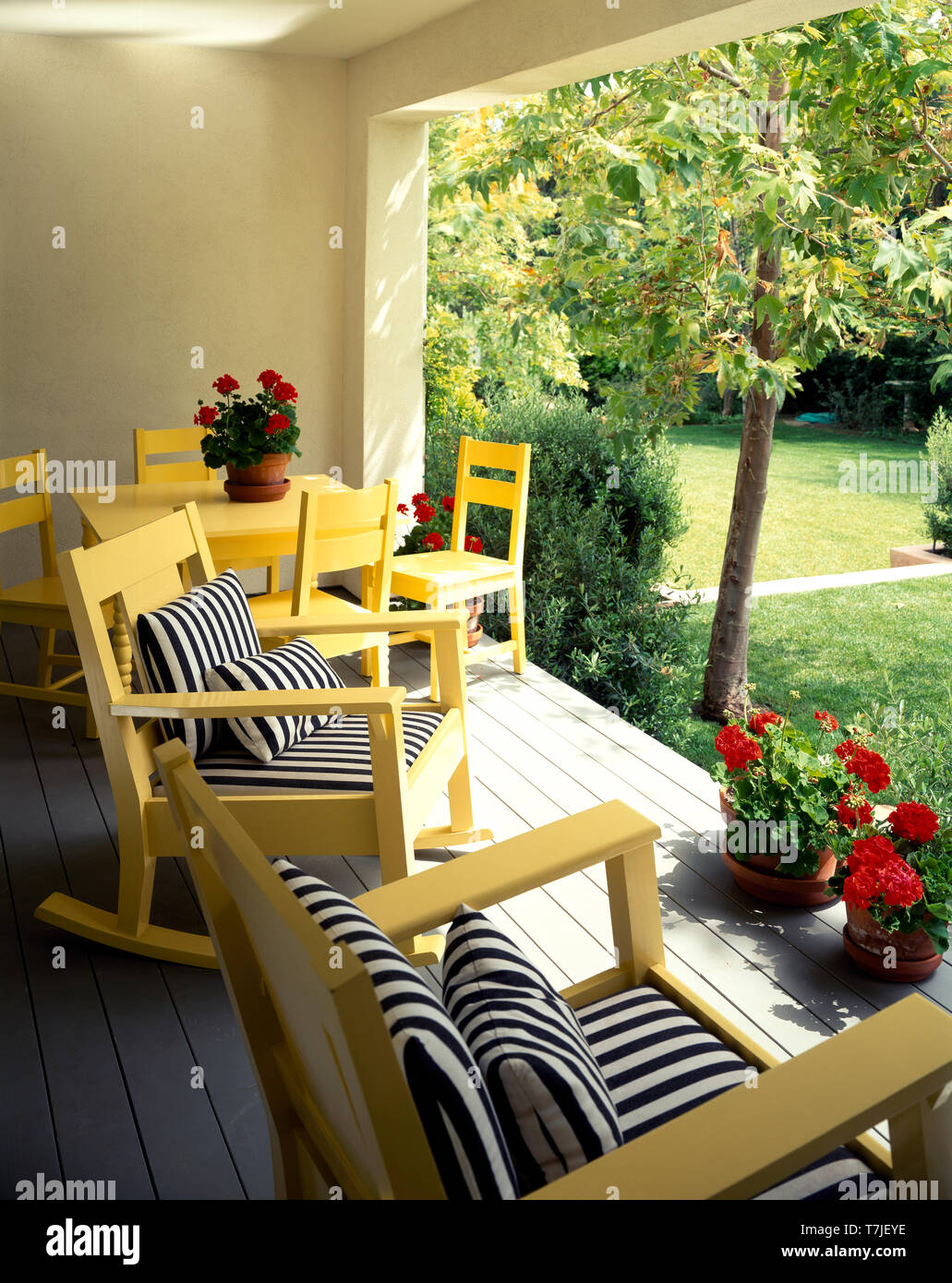 Black+white striped cushions on yellow chairs on veranda overlooking