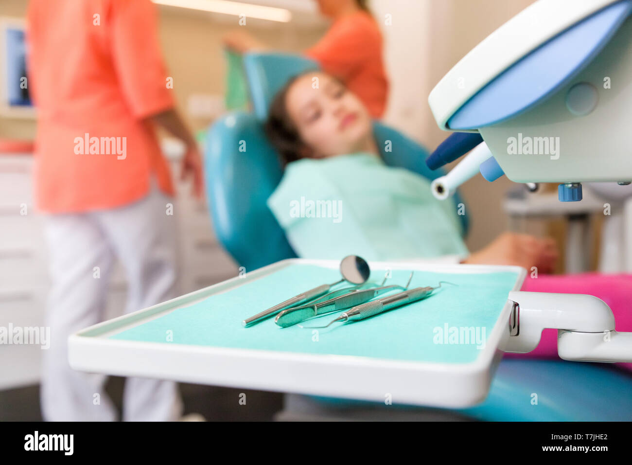 10-year-old girl at the dentist waiting for the checkup with dentist tools and instruments in the foreground Stock Photo