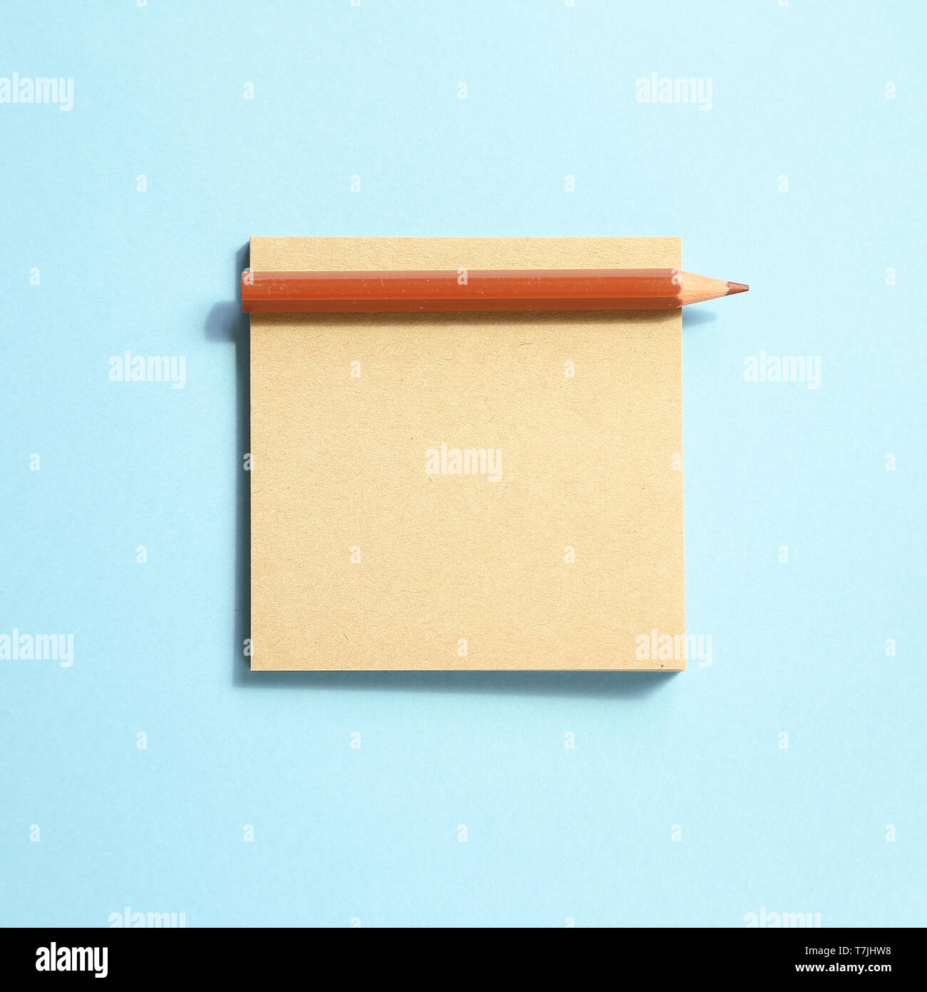 Memo note pad and brown colored pencil on blue background Stock Photo