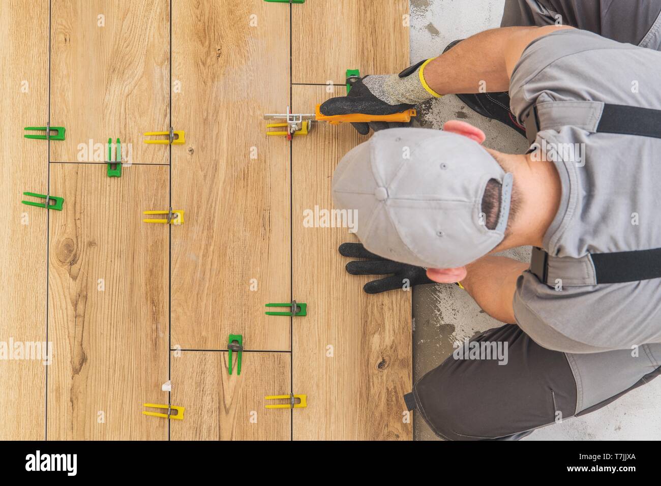 Professional Remodeling Worker Installing Wooden Like Ceramic Floor in the Kitchen Area. Home Renovation Project. Stock Photo