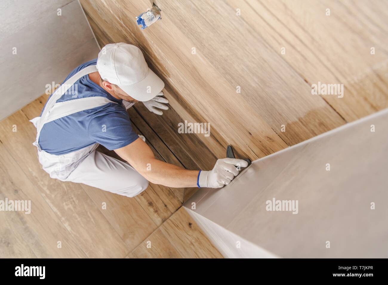 Sealing Finished Ceramic Tiles Bathroom Shower Cabin. Caucasian Construction Worker in HIs 30s. Industrial Theme. Stock Photo