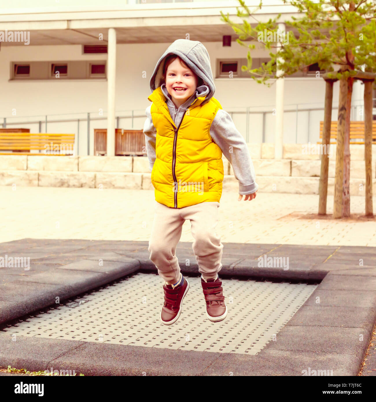 Happy child, active five year old boy plays outdoors in playground jumping high in the sky on trampoline Stock Photo