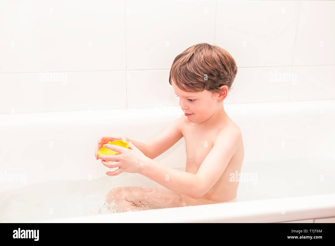 Five year old boy enjoying a bath having fun sitting in bathtub playing Stock Photo Alamy