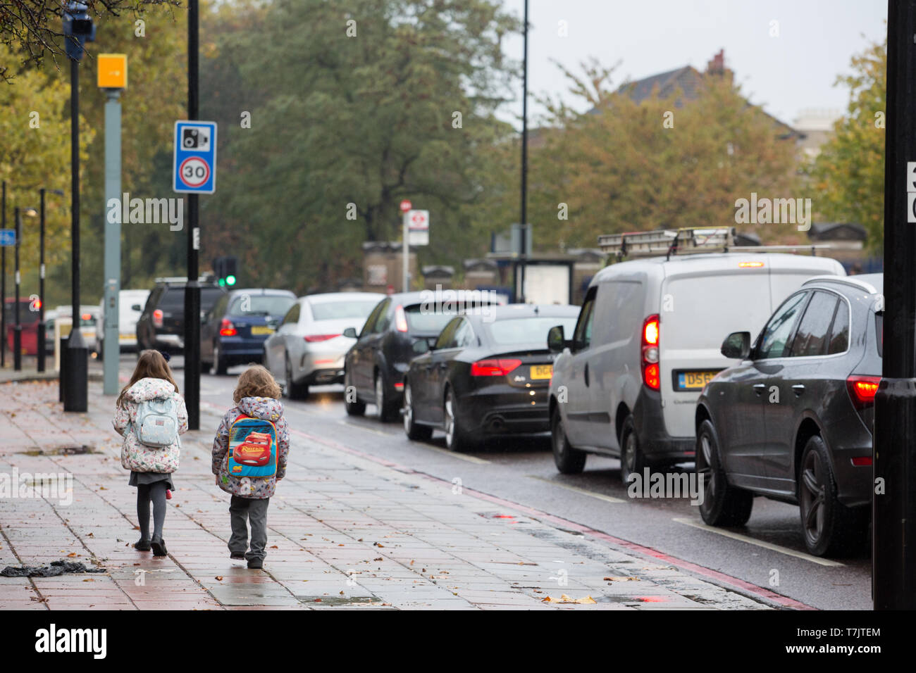 Young children walking to school next to a congested road in Wandsworth, London Stock Photo