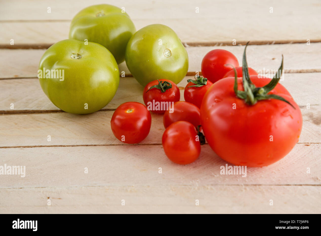 different types of tomatoes on a light wooden background Stock Photo ...