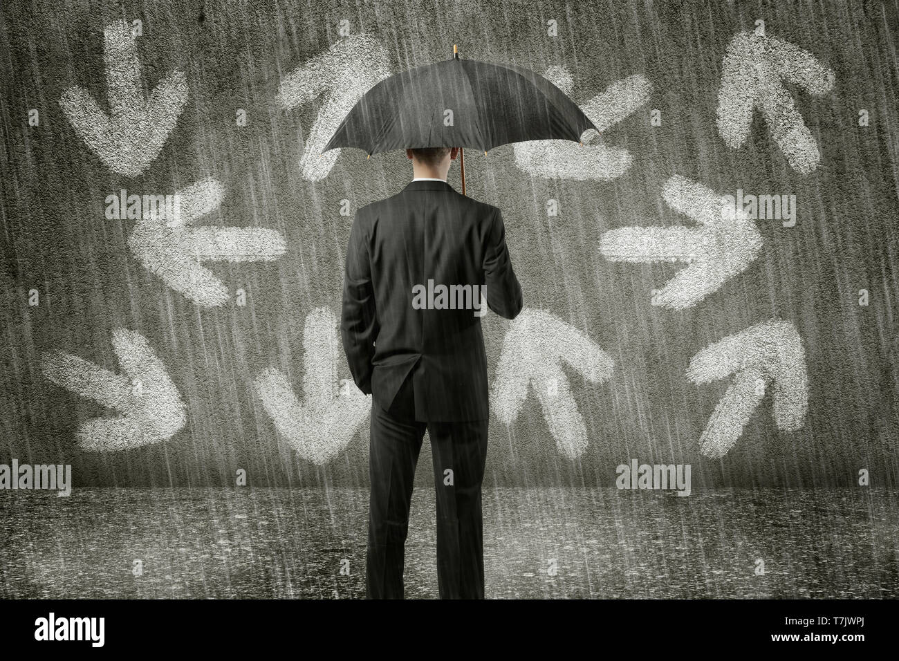confused businessman standing in front of wall on a gloomy day has to make a decision Stock Photo