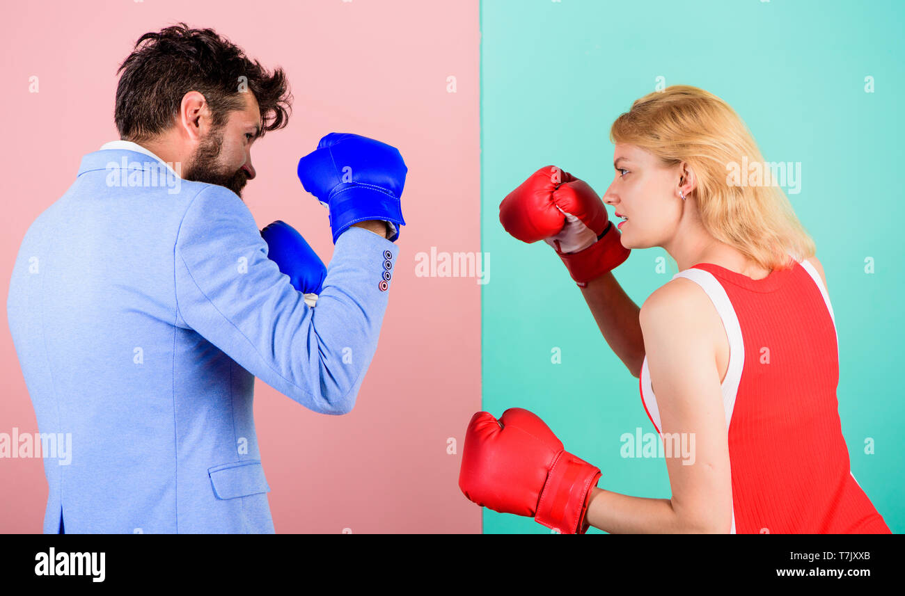 Man formal suit and athletic woman boxing fight. Couple in love competing in boxing. Female and male boxers fighting in gloves. Domination concept. Gender battle. Gender equal rights. Gender equality. Stock Photo